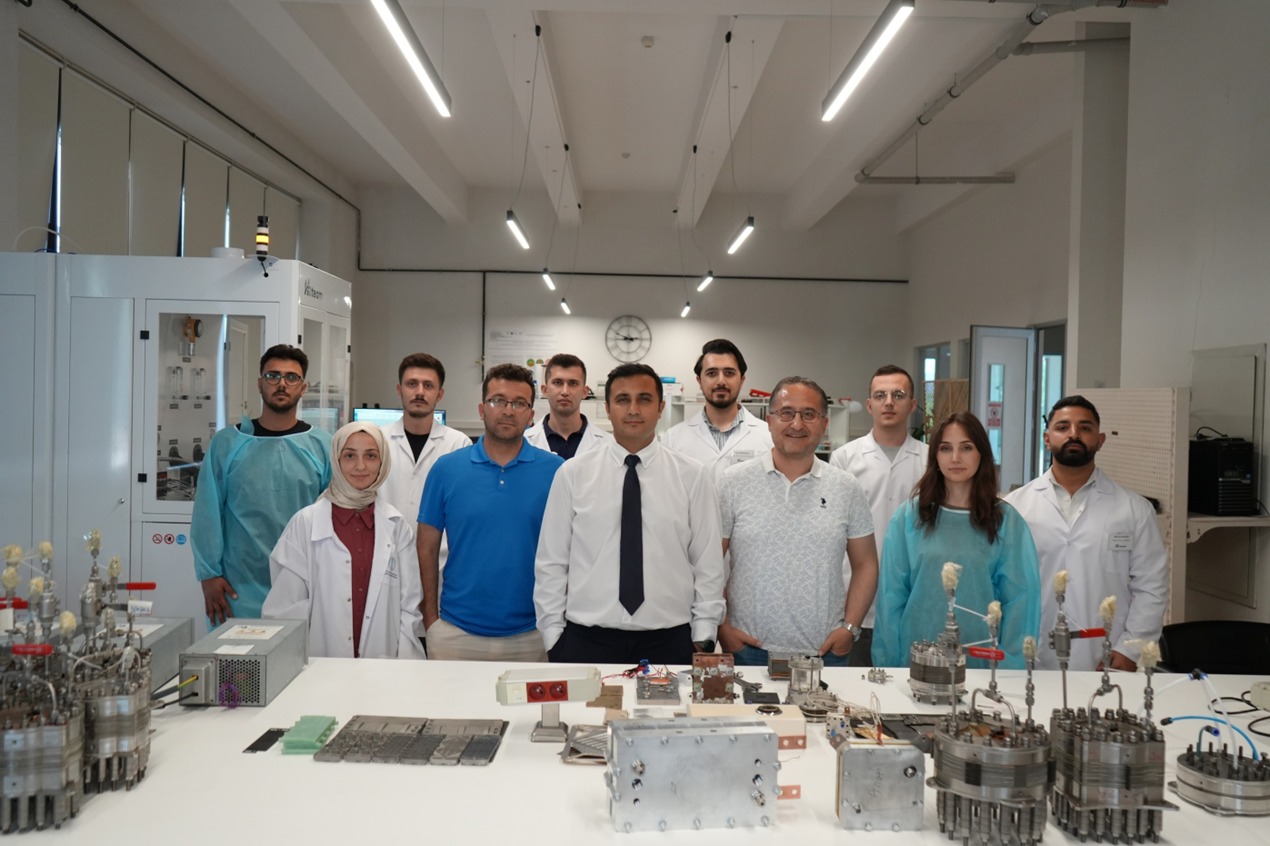 Laboratuvar masasının önünde çalışma ekibinin grup fotoğrafı