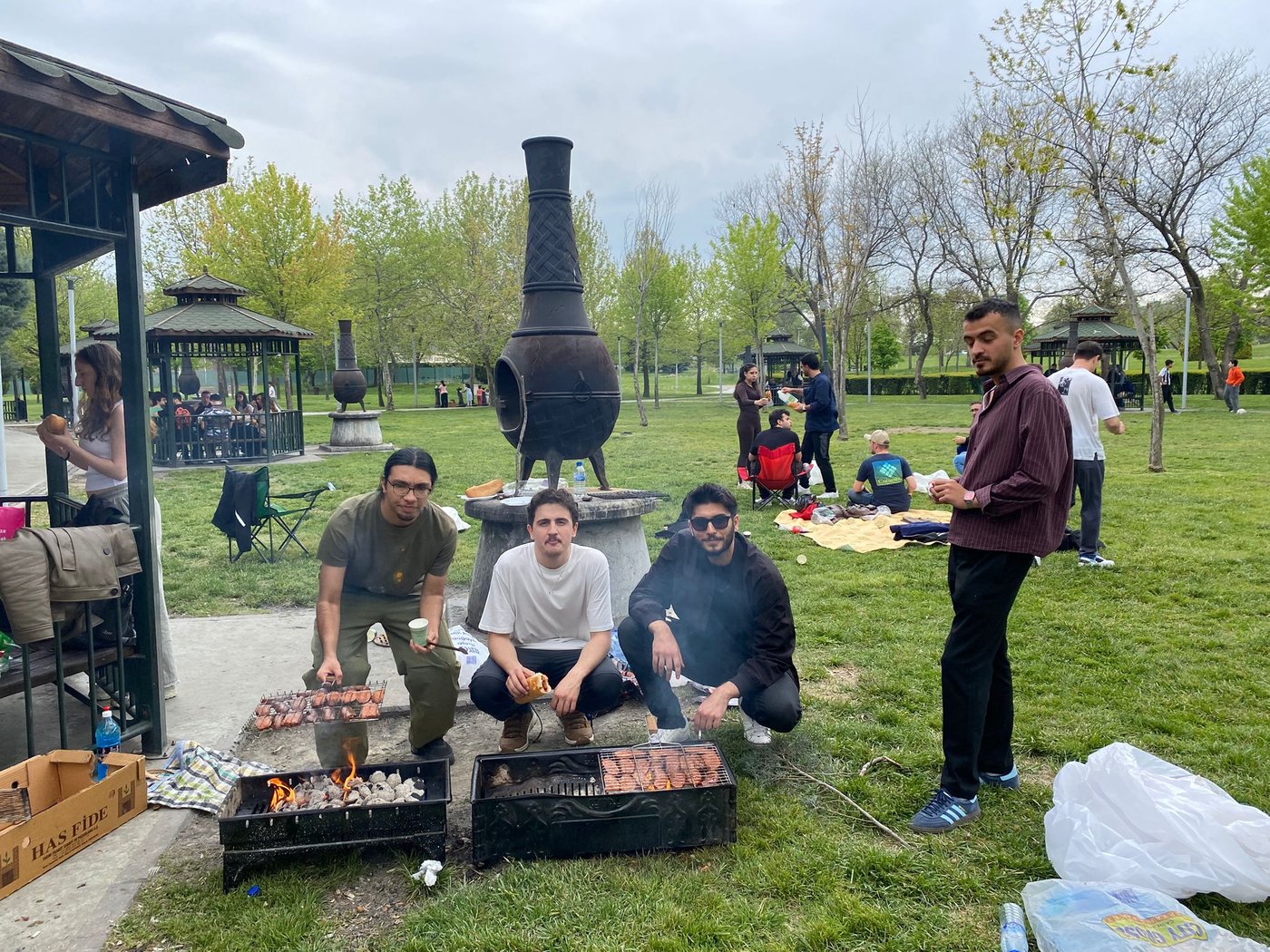 Students continue the picnic preparations together by grilling sausages on the barbecue.