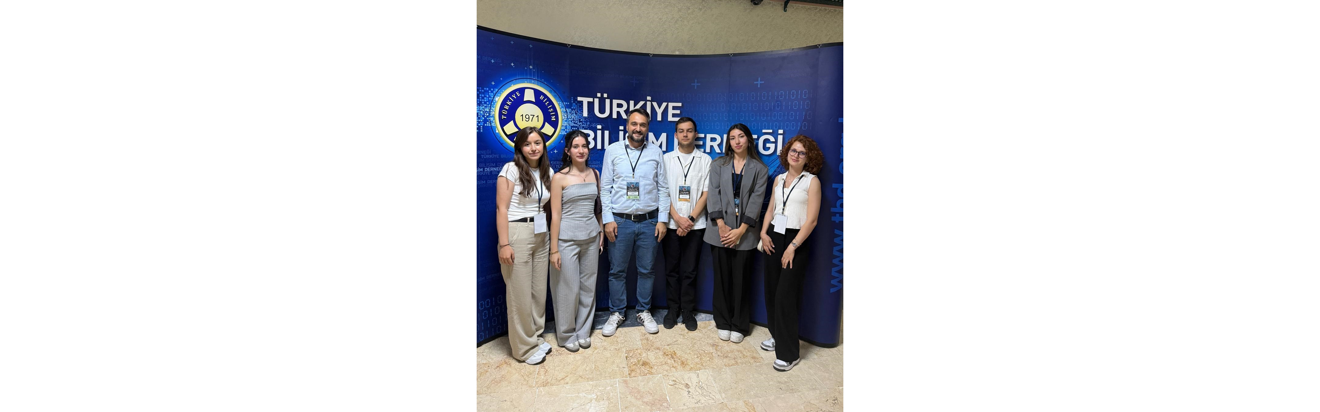 Genç Beyinler Yeni Fikirler proje yarışmasında Türkiye Bilişim Derneği standının önünde grup fotoğrafı.