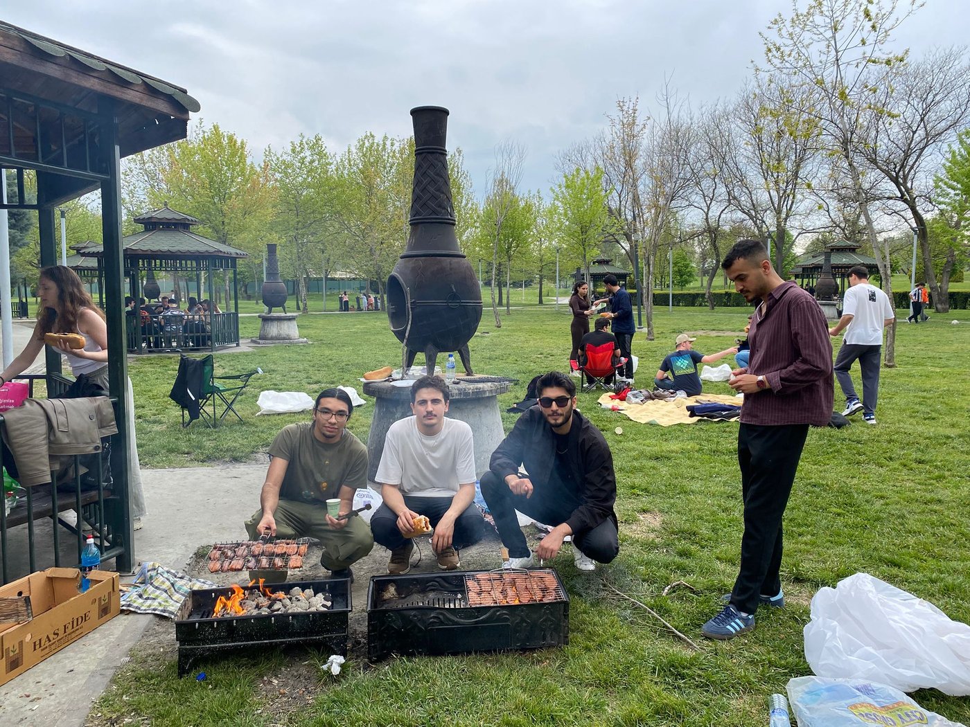 Students spend time together while grilling sausages at the picnic area barbecue.