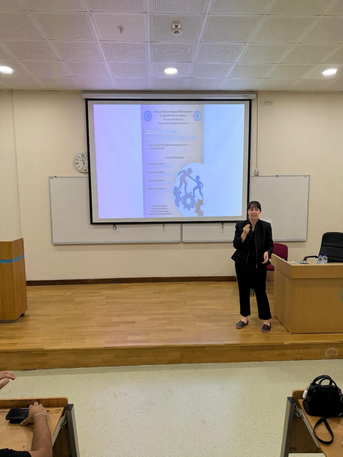 4. sınıf öğrencilerine Doç. Dr. Reyhan Eskiyurt tarafından Mentör Menti Programı afişi tanıtılıyor.