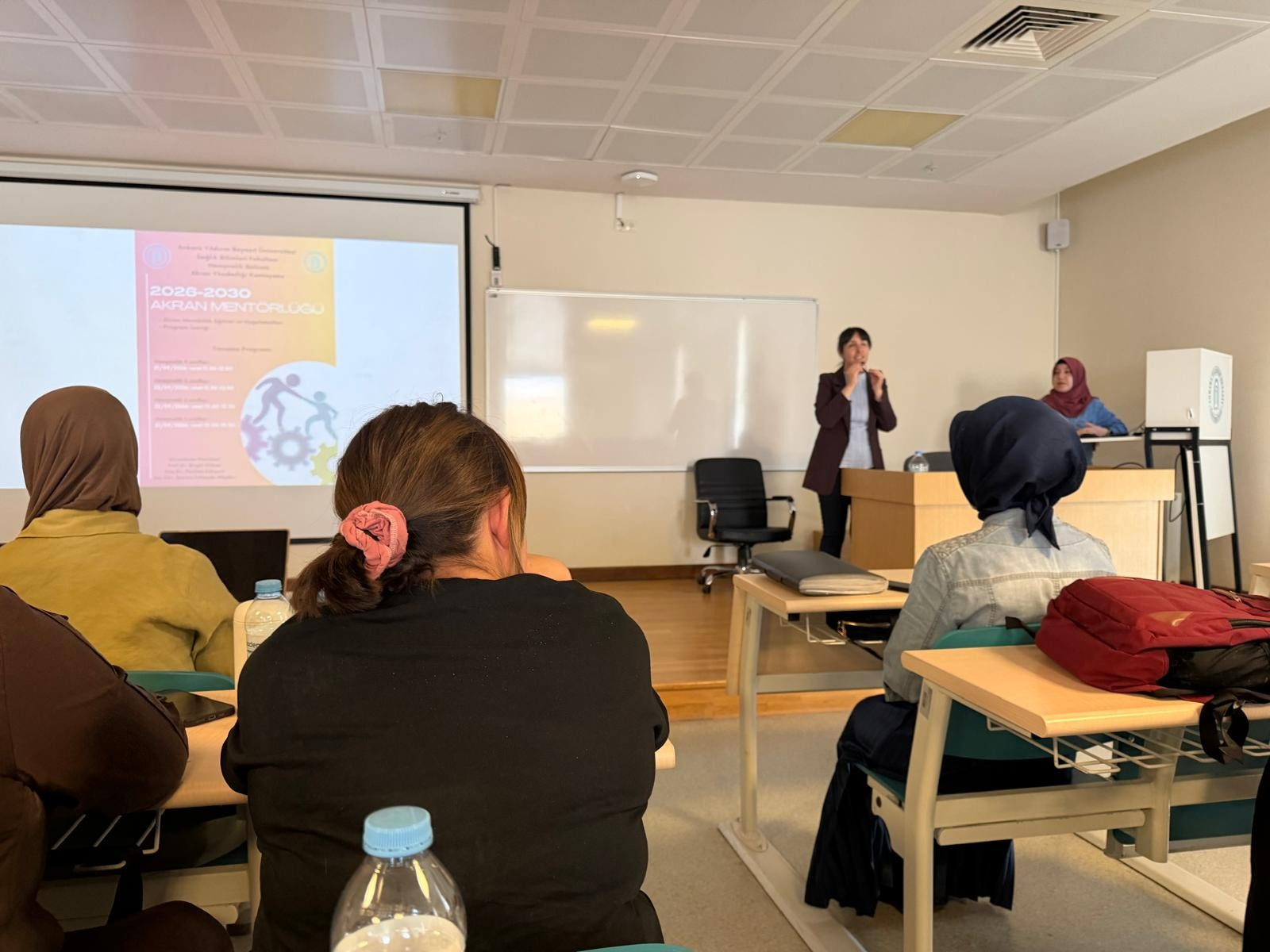3. sınıf öğrencilerine Doç. Dr. Reyhan Eskiyurt ve Arş. Gör. Şeyma ALBAKIR tarafından Mentör Menti Programı afişi tanıtılıyor. 