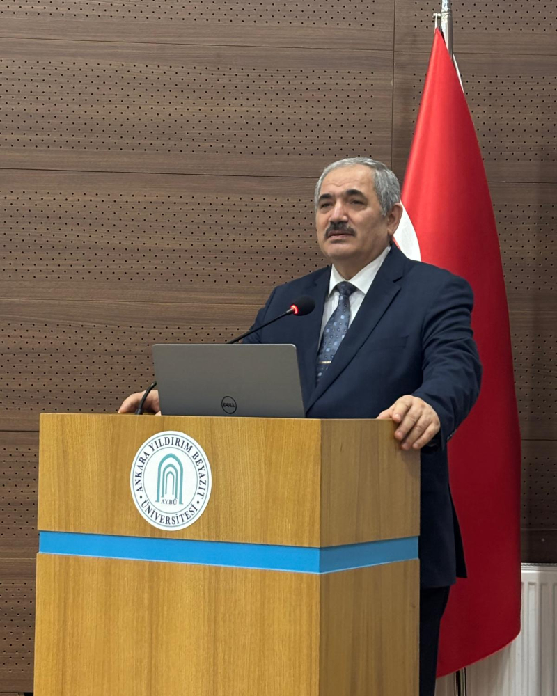 İlahiyat Fakültesi Dekanı Prof. Dr. Nuri ADIGÜZEL, konferans salonunda kürsü önünde bilgilendirme konuşması yaparken.