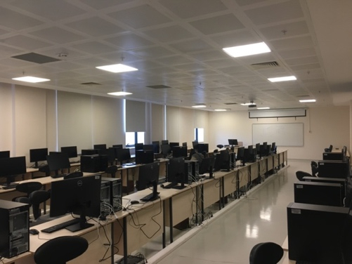 L104 Bilgisayar Laboratuvarında sıralı bilgisayarlar, çalışma koltukları ve cam yüzeyli çizim masaları.