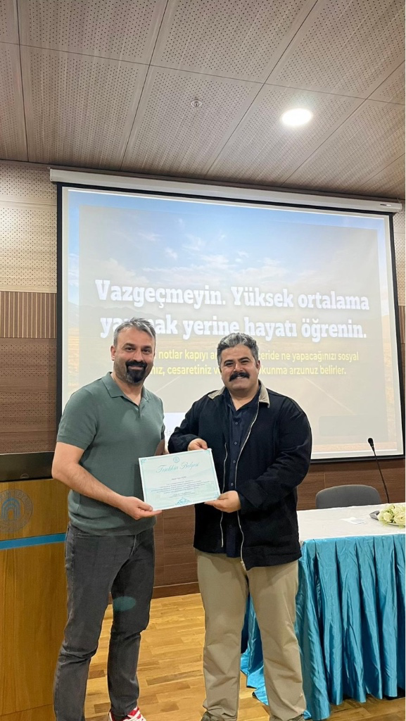 Oğuz Kuru'nun Dr.Öğr.Üyesi Erdinç Alaca'dan belgesini alırken çekilmiş bir fotoğrafı